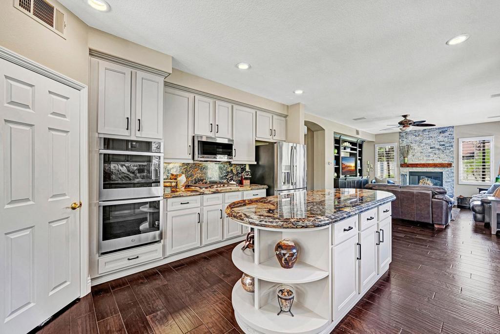 1463 Belmont Park Road Oceanside, CA 92057 - Photo 17 of 50 a kitchen with kitchen island granite countertop a stove top oven a chimney cabinets and wooden floor