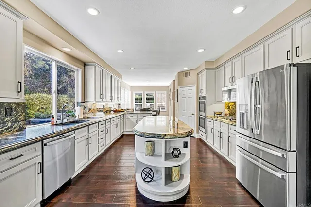 a kitchen with stainless steel appliances granite countertop a refrigerator a stove and a sink