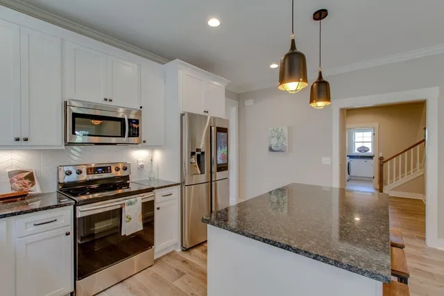 a kitchen with stainless steel appliances granite countertop a sink a stove and a refrigerator
