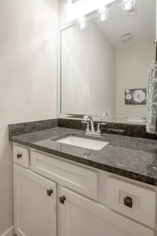 a bathroom with a granite countertop sink and vanity