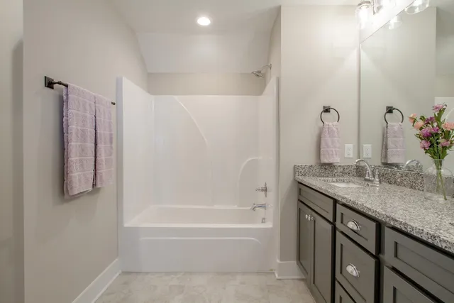 a bathroom with a granite countertop sink a mirror and a bathtub