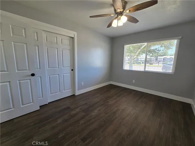 an empty room with wooden floor chandelier fan and windows