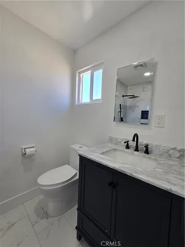 a bathroom with a granite countertop sink a toilet and a mirror