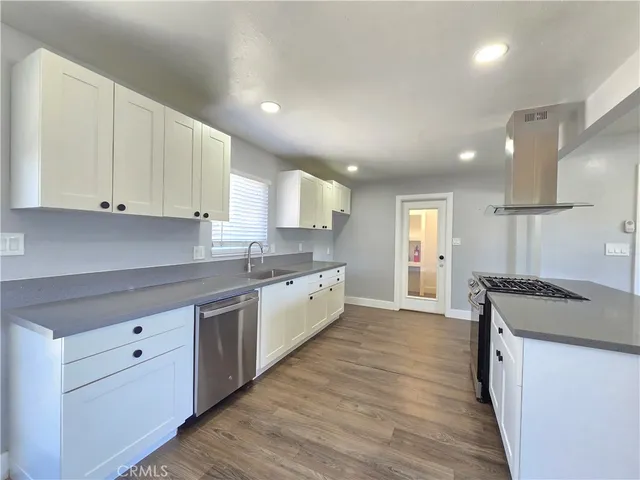 a large kitchen with stainless steel appliances granite countertop a stove a sink and white cabinets