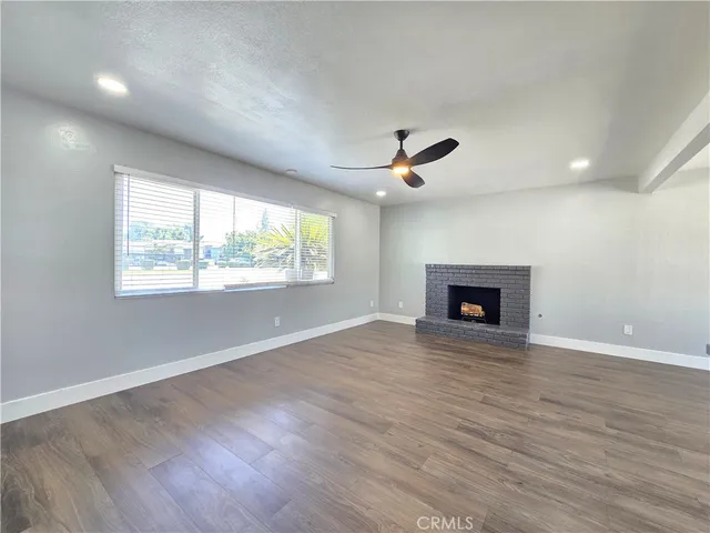 an empty room with windows fireplace and wooden floor