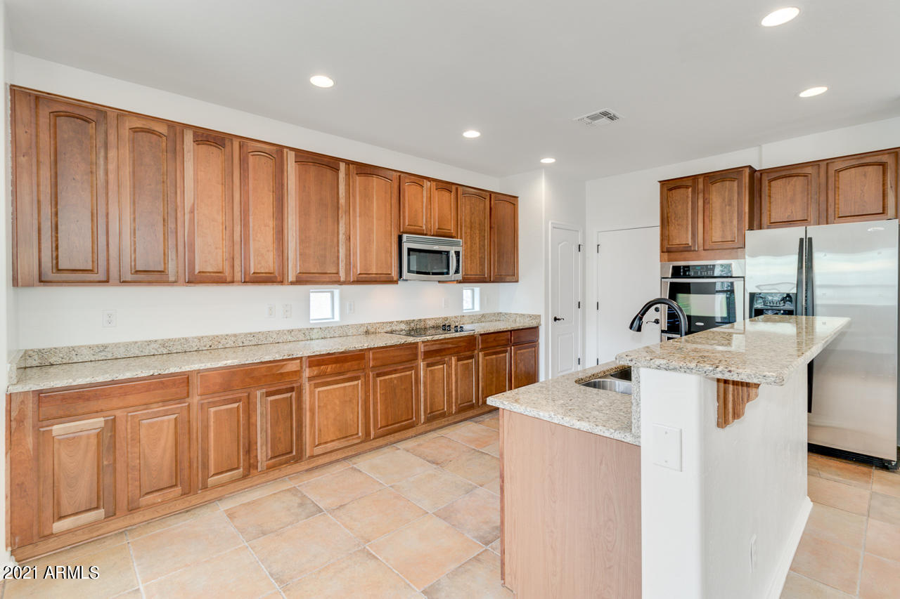 1074 South Hawk Lane Gilbert, AZ 85296 - Photo 11 of 35 a kitchen with granite countertop a sink stove and refrigerator