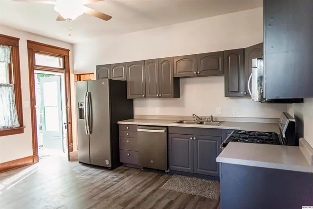 a kitchen with stainless steel appliances a refrigerator a sink and wooden cabinets