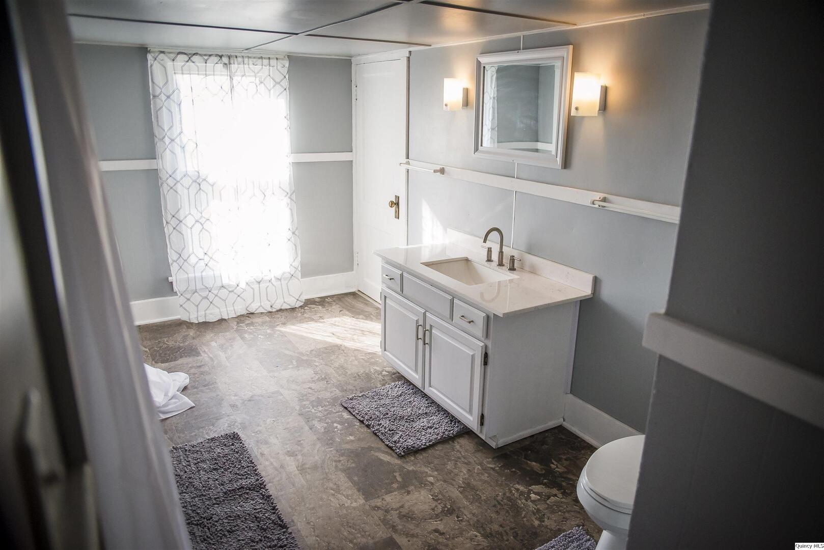 512 Madison Street Quincy, IL 62301 - Photo 5 of 15 a bathroom with a sink a toilet and a mirror