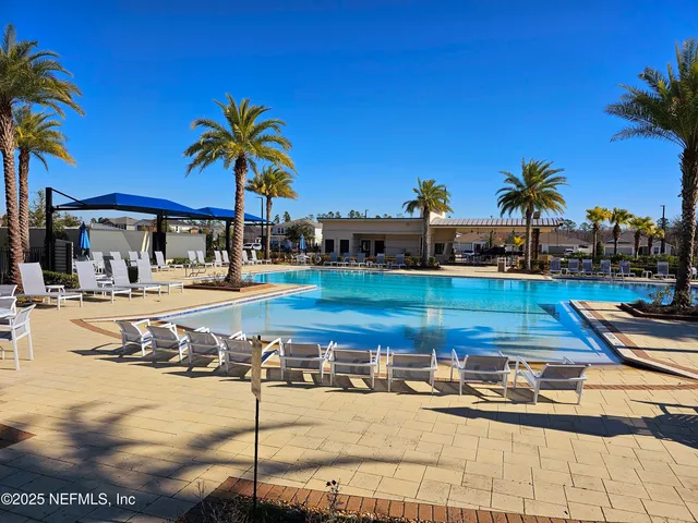 a view of a swimming pool with a lawn chairs under an umbrella