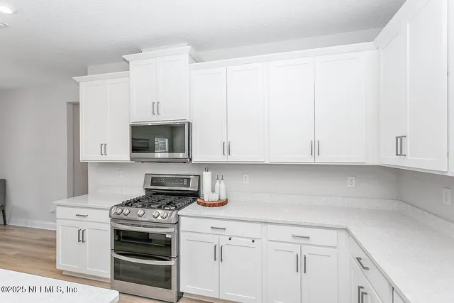 a kitchen with granite countertop white cabinets and stainless steel appliances