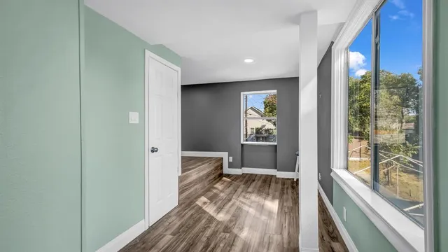 a view of an empty room with wooden floor and a window