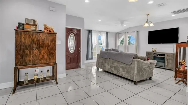 a living room with furniture a flat screen tv and a refrigerator