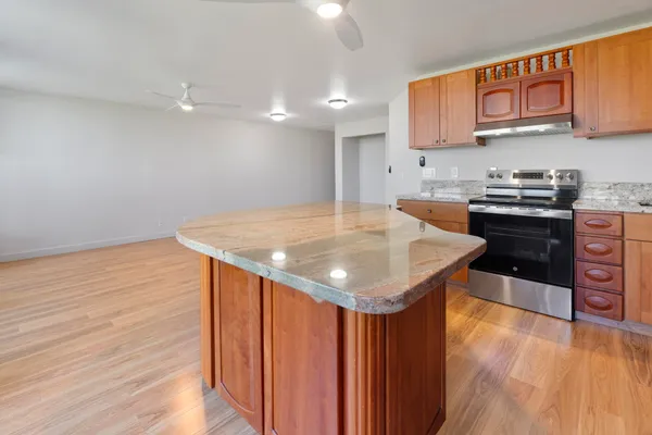 a kitchen with stainless steel appliances granite countertop a sink a stove and a wooden floors