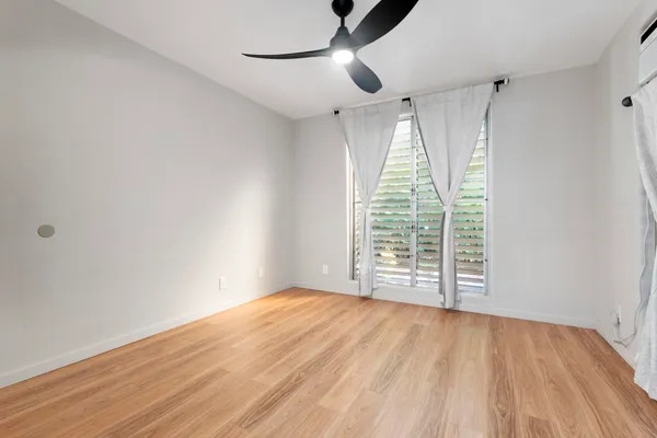 a view of an empty room with wooden floor and a window