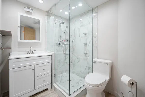 a bathroom with a shower sink mirror and toilet