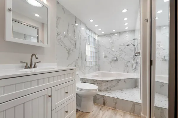 a bathroom with a bathtub shower sink mirror and toilet