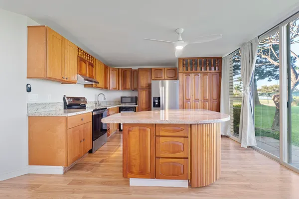 a kitchen with stainless steel appliances granite countertop a stove a sink dishwasher and a refrigerator with wooden floor
