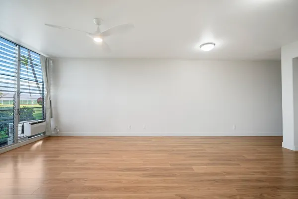 a view of an empty room with wooden floor and a window