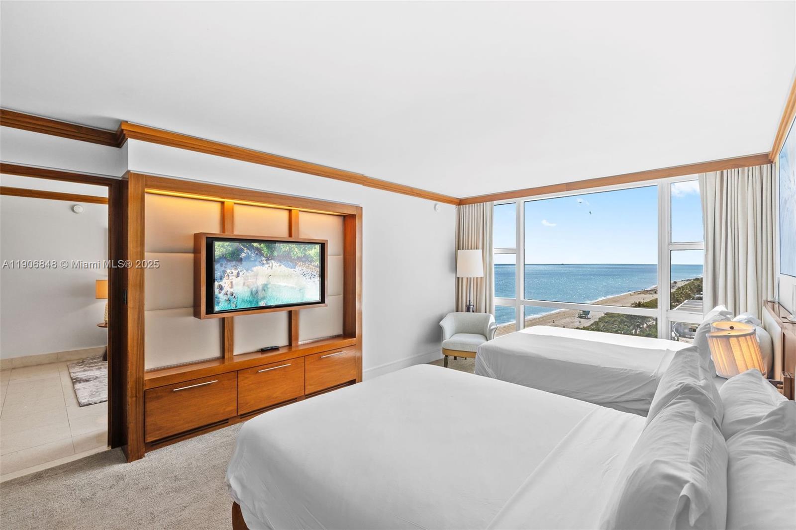 6801 Collins Avenue, Unit 1018 Miami Beach, FL 33141 - Photo 8 of 26 a bedroom with two beds and a flat screen tv