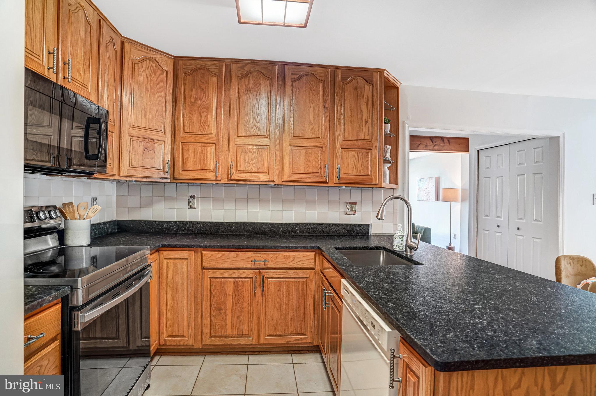 7709 Brandon Way Manassas, VA 20109 - Photo 12 of 40 a kitchen with granite countertop a sink a stove and cabinets