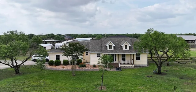 a front view of a house with a garden and a tree