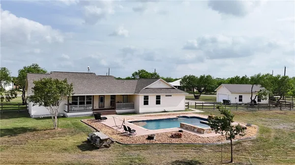 a house with swimming pool and trees in the background