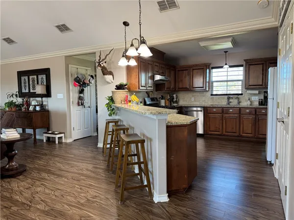 a kitchen with stainless steel appliances granite countertop a refrigerator a stove top oven a sink dishwasher and dining table with wooden floor
