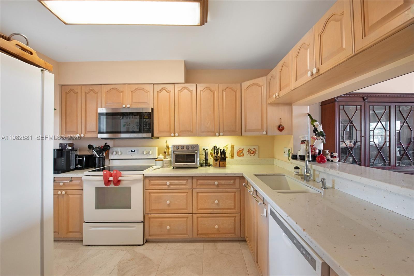 3050 Northeast 48th Court, Unit 401 Lighthouse Point, FL 33064 - Photo 12 of 35 a kitchen with a sink dishwasher stove and white cabinets