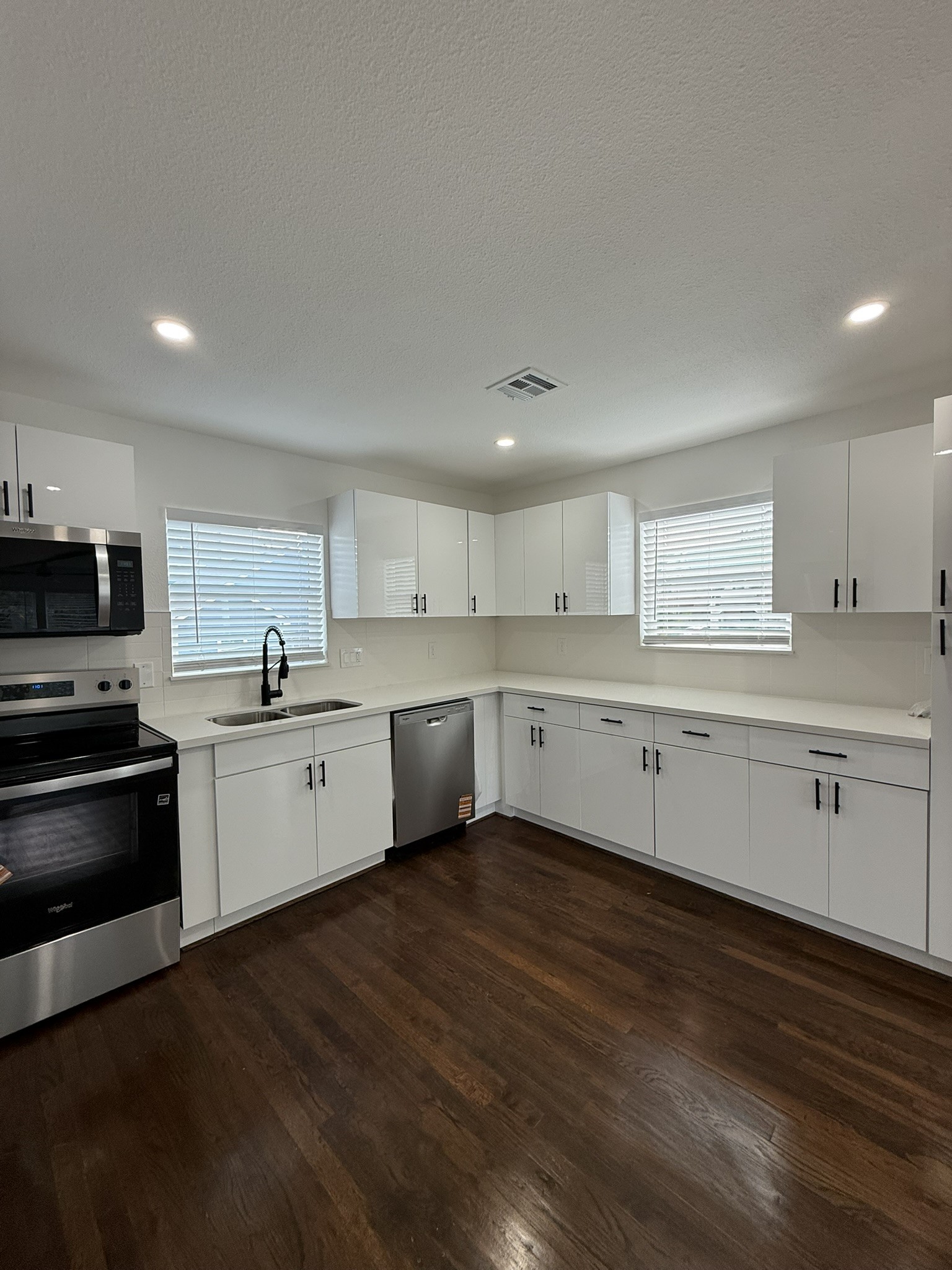 705 Stanford Street, Unit A Houston, TX 77019 - Photo 6 of 16 a large white kitchen with a stove a sink and dishwasher with wooden floor