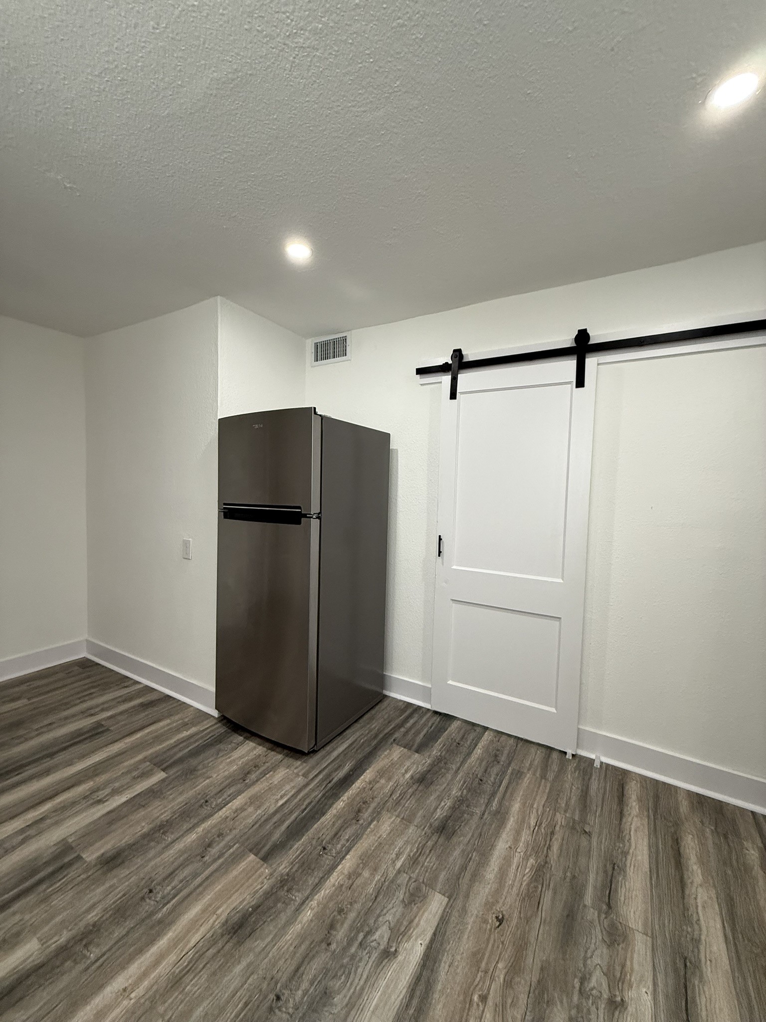 705 Stanford Street, Unit A Houston, TX 77019 - Photo 8 of 16 a view of a refrigerator in kitchen and an empty room with wooden floor