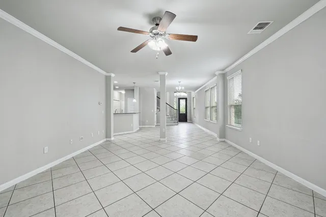 a view of an empty room and chandelier fan