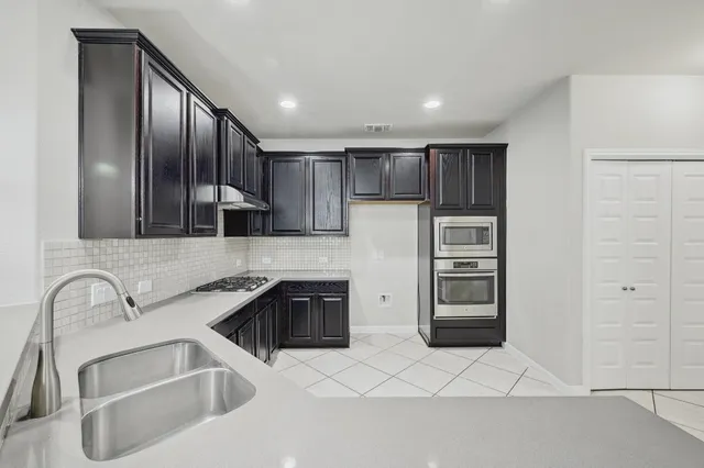 a kitchen with stainless steel appliances granite countertop a sink and a refrigerator