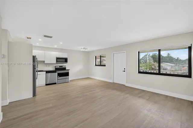 a view of kitchen with stainless steel appliances kitchen island wooden floor and window