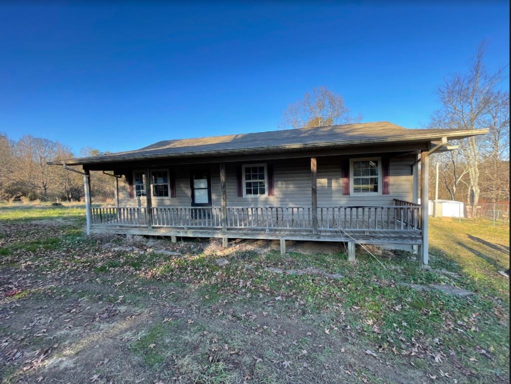 a view of a house with wooden deck and a forest