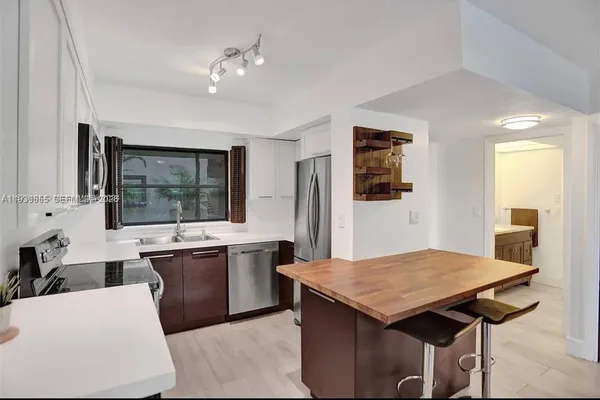 a kitchen with a stove a sink dishwasher and a refrigerator with wooden floor