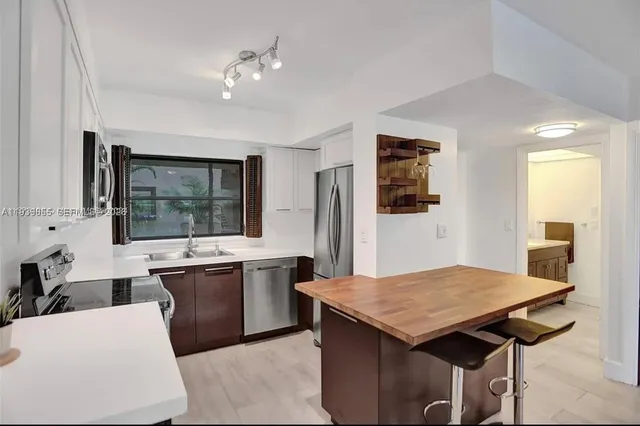 a kitchen with a stove a sink dishwasher and a refrigerator with wooden floor