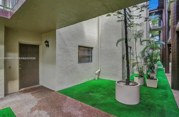 a view of a small house with a potted plant and a yard