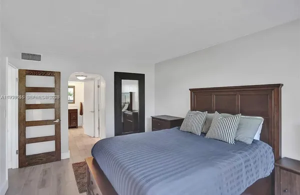 a bedroom with a large bed and wooden floor