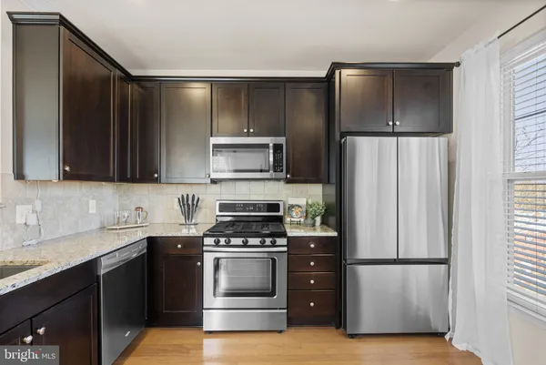 a kitchen with stainless steel appliances granite countertop a refrigerator a stove a sink and a microwave