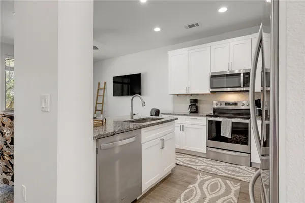 a kitchen with stainless steel appliances granite countertop a stove a sink and a refrigerator