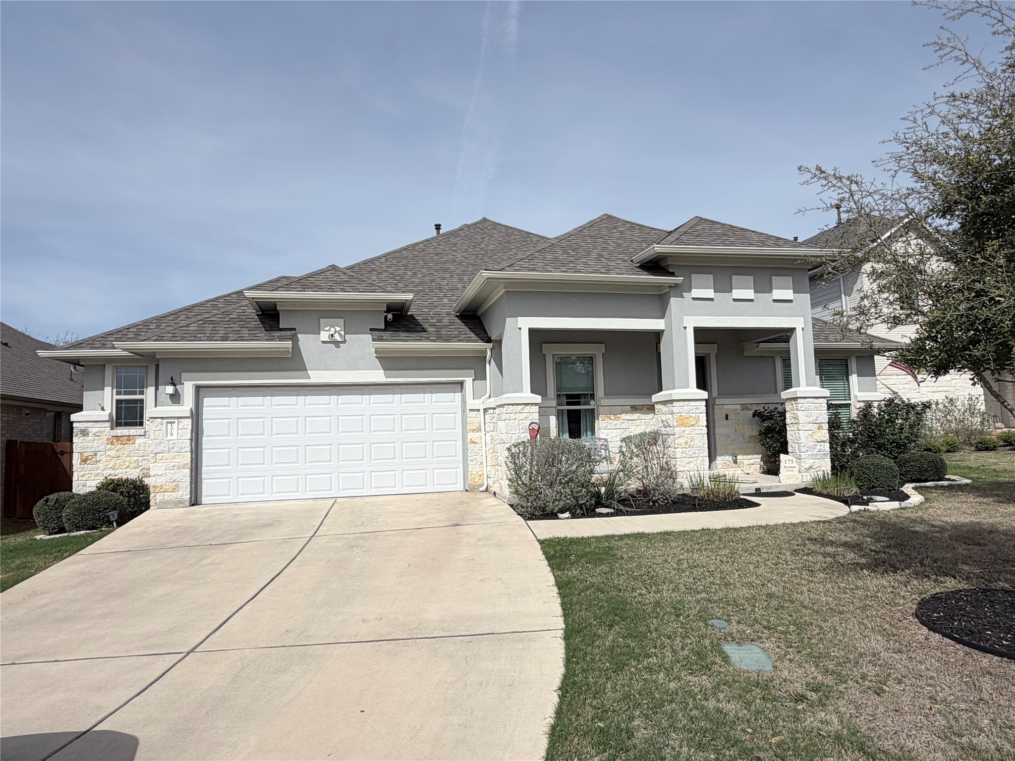 175 Bonham Cove Dripping Springs, TX 78620 - Photo 1 of 1 Prairie-style house with a garage, stone siding, driveway, and roof with shingles