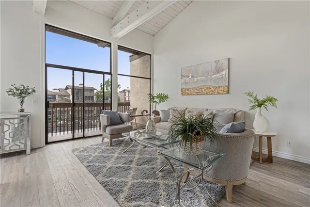 a living room with furniture large window and wooden floor