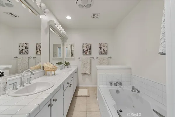 a bathroom with a tub sink double vanity and mirror