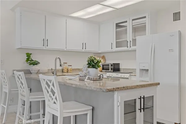 a kitchen with stainless steel appliances granite countertop a table chairs in it and white cabinets