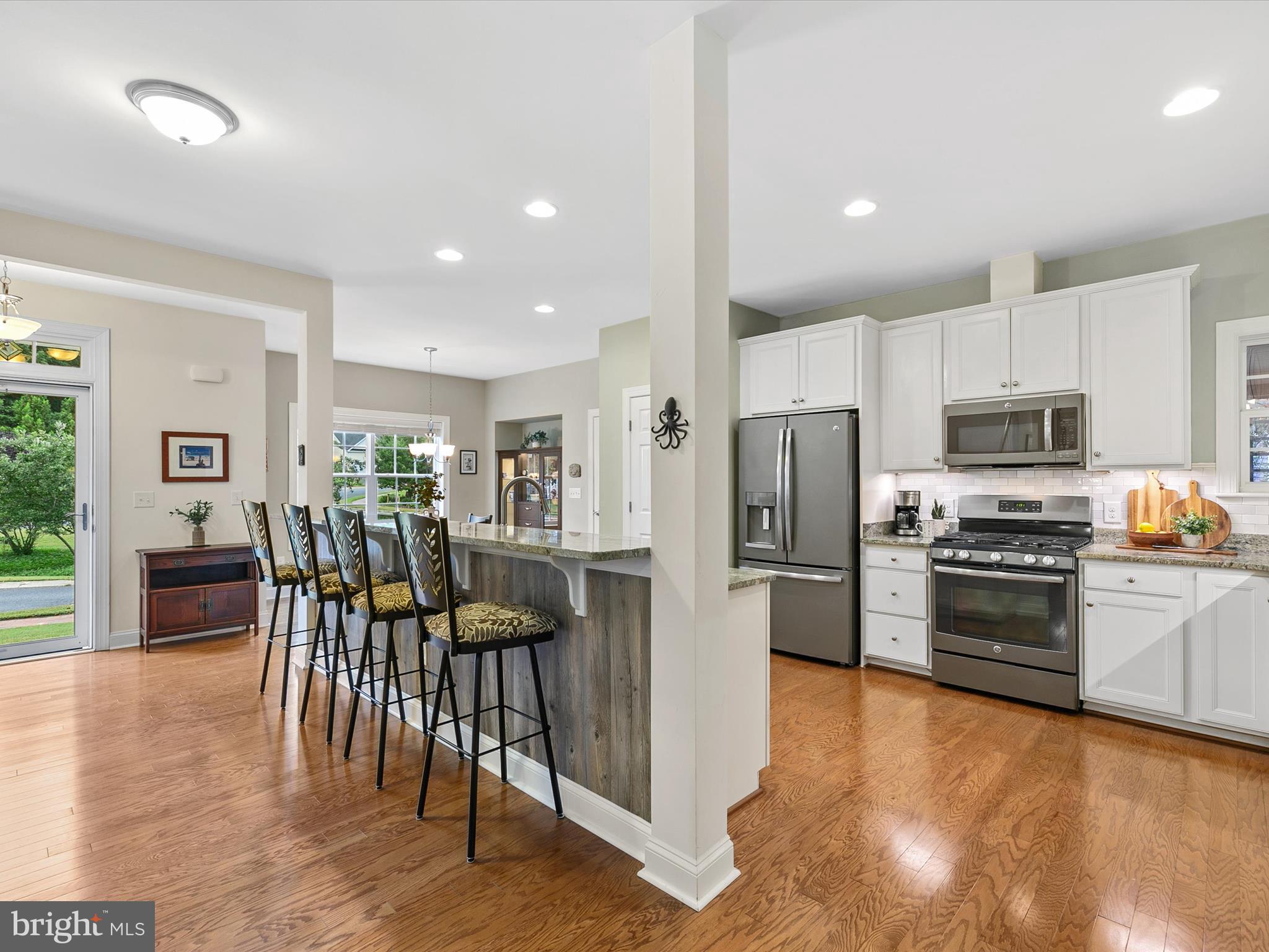 303 Valley Road Milton, DE 19968 - Photo 7 of 72 a kitchen with stainless steel appliances kitchen island granite countertop a refrigerator a stove a sink a dining table and chairs with wooden floor
