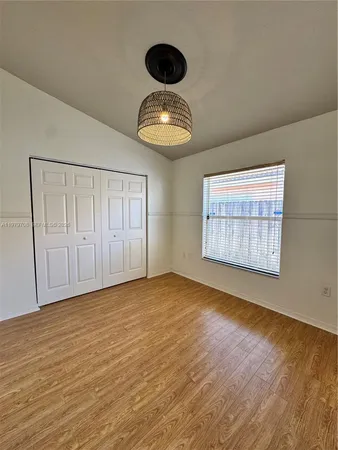 a view of an empty room with wooden floor and cabinets