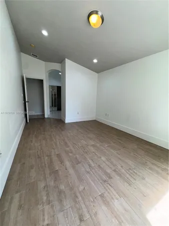an empty room with wooden floor and natural light
