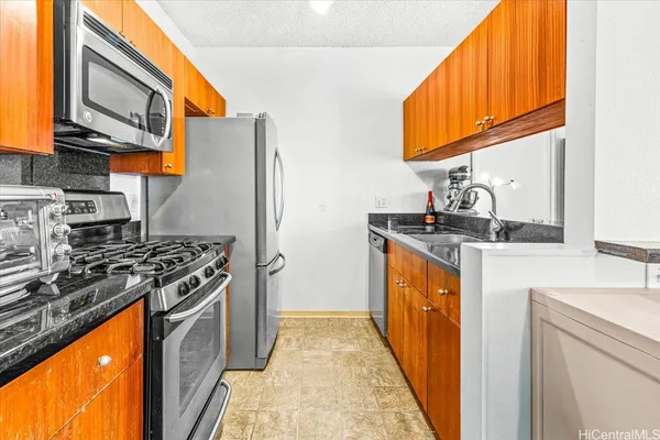a kitchen with stainless steel appliances granite countertop a stove top oven a refrigerator a sink and dishwasher