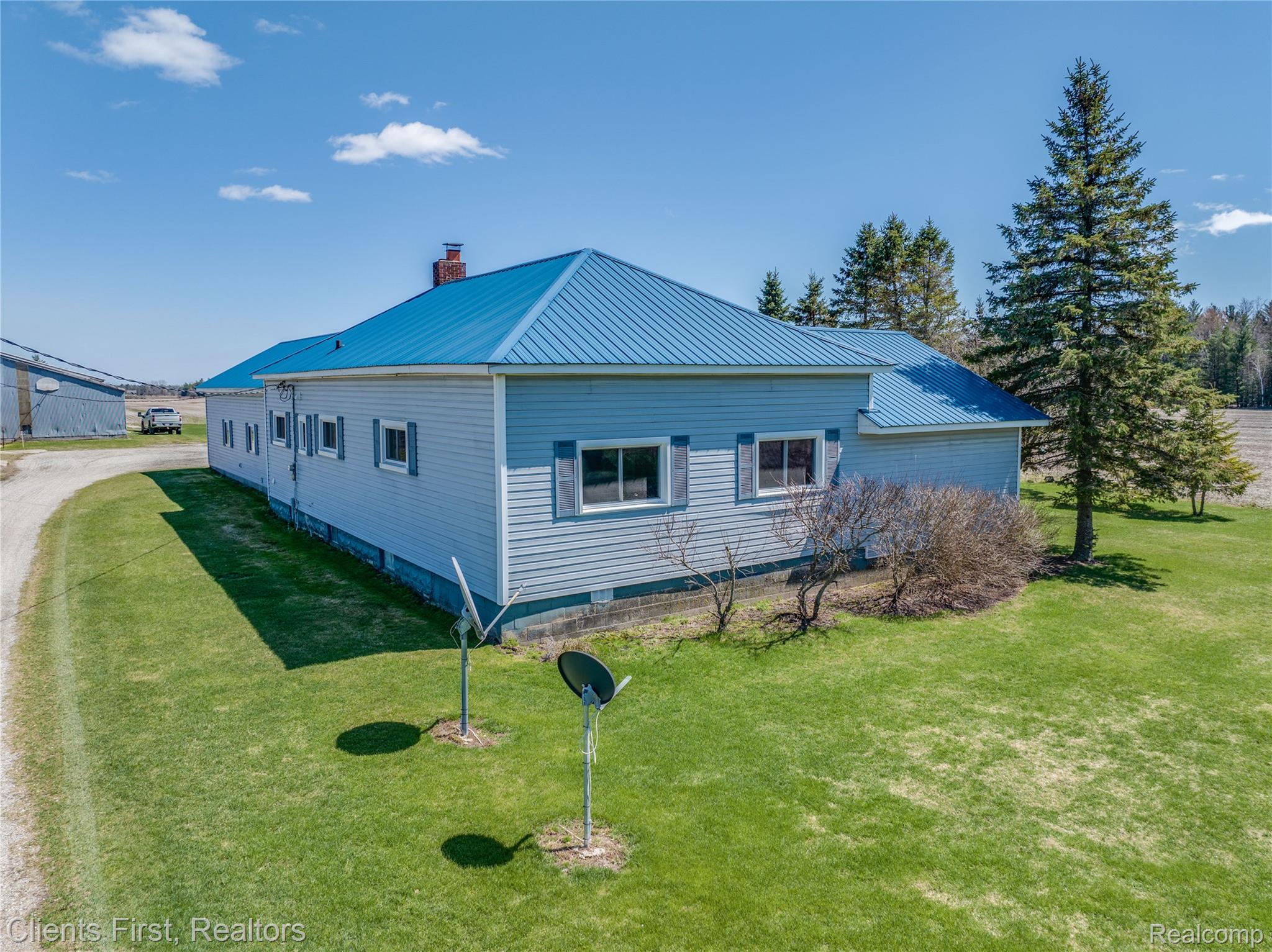 342 North Chambers Road Tawas City, MI 48763 - Photo 26 of 30 View of home's exterior featuring a metal roof, a chimney, and a lawn