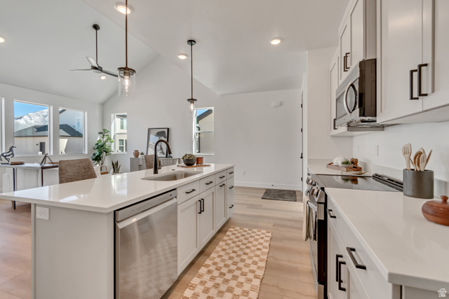 1302 1475 East, Unit 40 Payson, UT 84651 - Photo 8 of 34 Kitchen with stainless steel appliances, a center island with sink, white cabinetry, light wood finished floors, and vaulted ceiling
